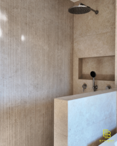 The view of the master bath in villa B at Bief à Danse with a half-walled shower and nook for bath products.