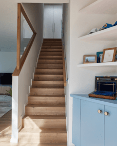 Un escalier en bois chalereux avec son balustrade en verre qui ajoute de la lumière dans la montée