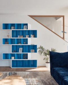 Une bibliothèque asymmetrique bleu ajoute un pop de couleur dans le salon